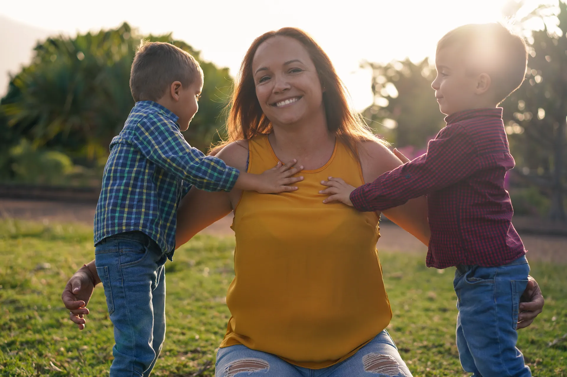 Mother smiling with two young children at sunset