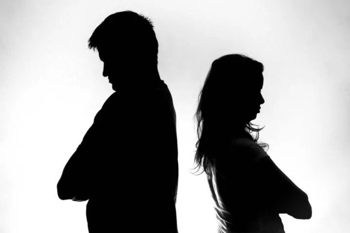 Silhouette of a man and woman standing back-to-back with arms crossed